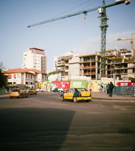 Street scene in Dakar with construction cranes, cars, and new buildings under construction.